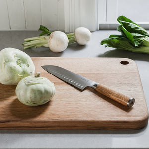 Løve Steig Santoku kniv i bruk på et skjærebrett med friske grønnsaker, den perfekte kniven for matlaging med effektivt og stilrent design.