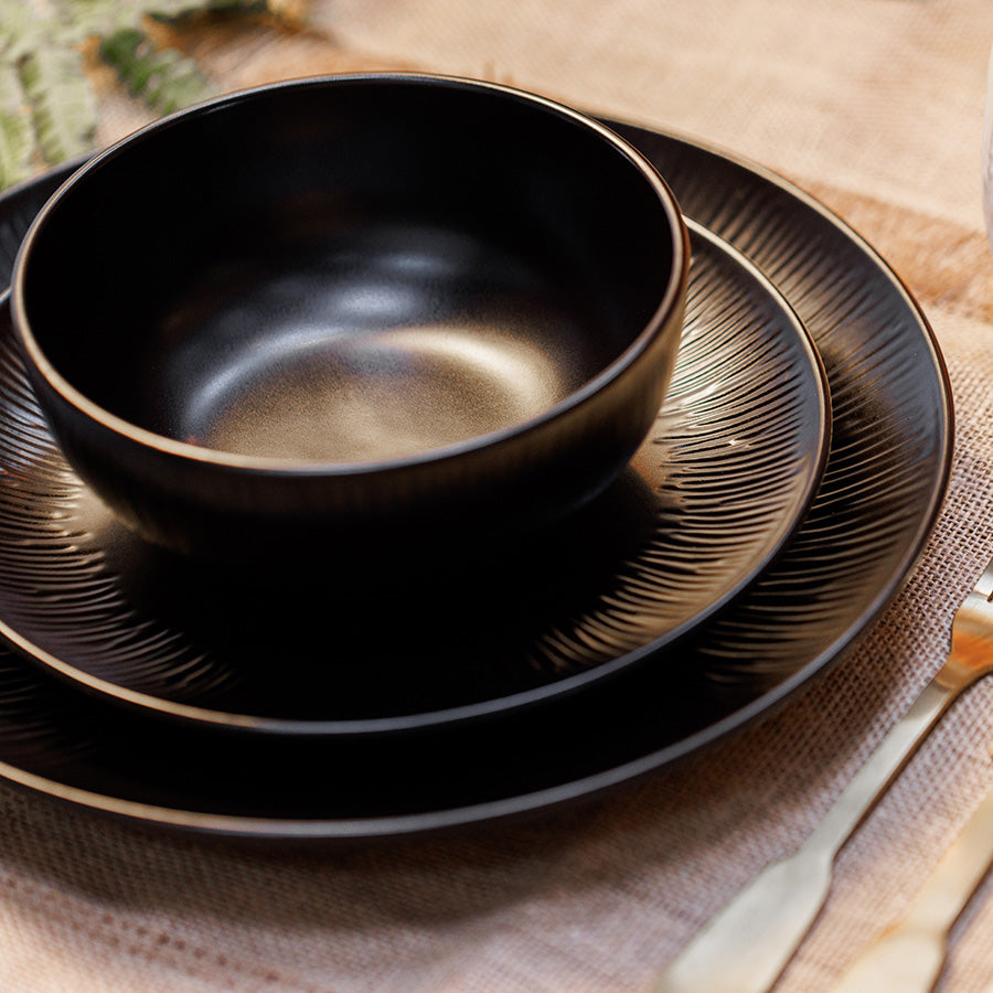 Vakkert oppsatt Mikasa Middagsservise Jardin Midnight 12 Deler Sort med ulike tallerkener og skåler plassert på et naturlig stoff.