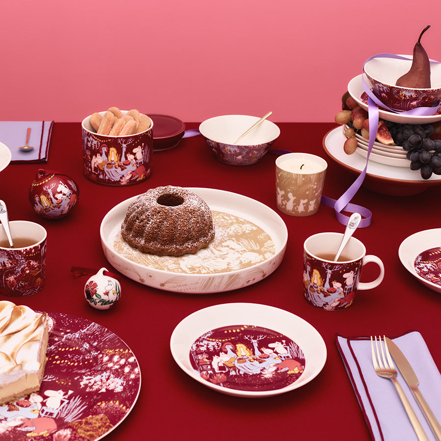 Festlig oppsett med Mummi bolle fra Moomin Arabia, inkludert flere serveringsfat og kopper, perfekt for julefeiring.