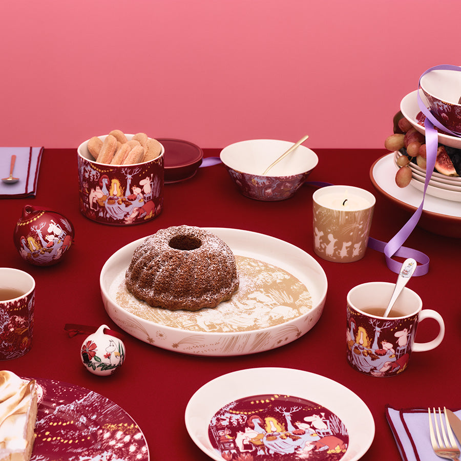 Moomin Arabia paiform satt i en festlig samling av servise og bakverk, perfekt for høytider og sammenkomster.