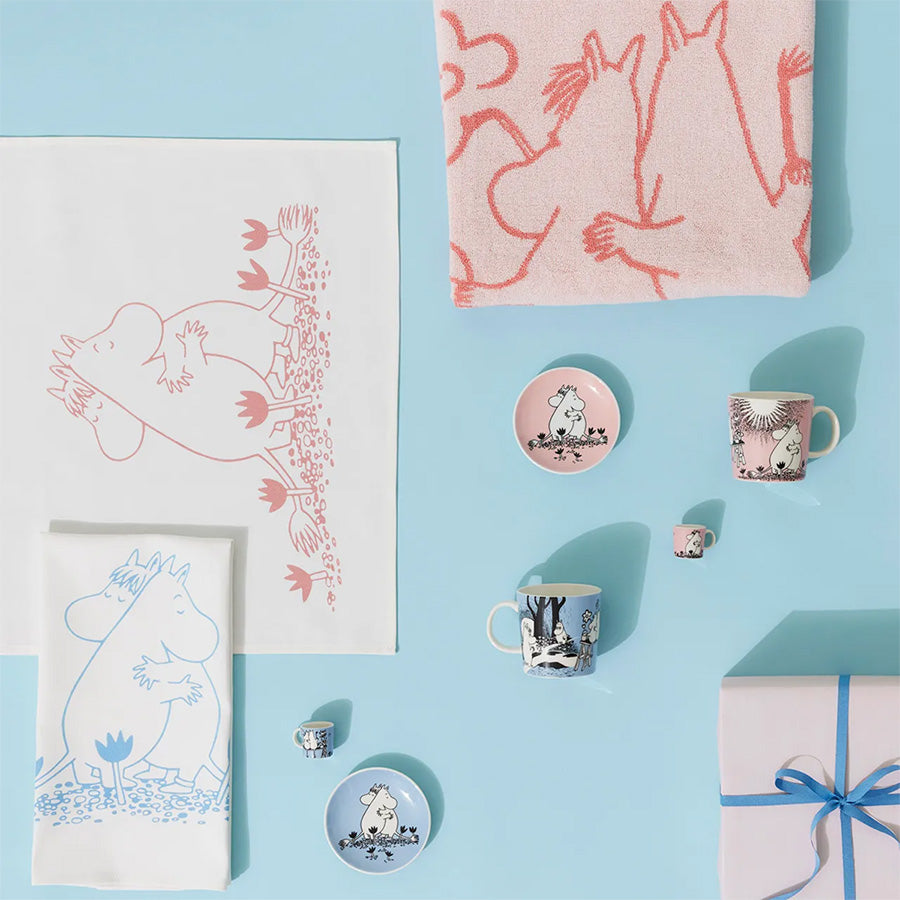 Variert utvalg av Moomin Arabia produkter inkludert minikopper og duk, moderne interiørdetaljer med Mummi-tematikk.