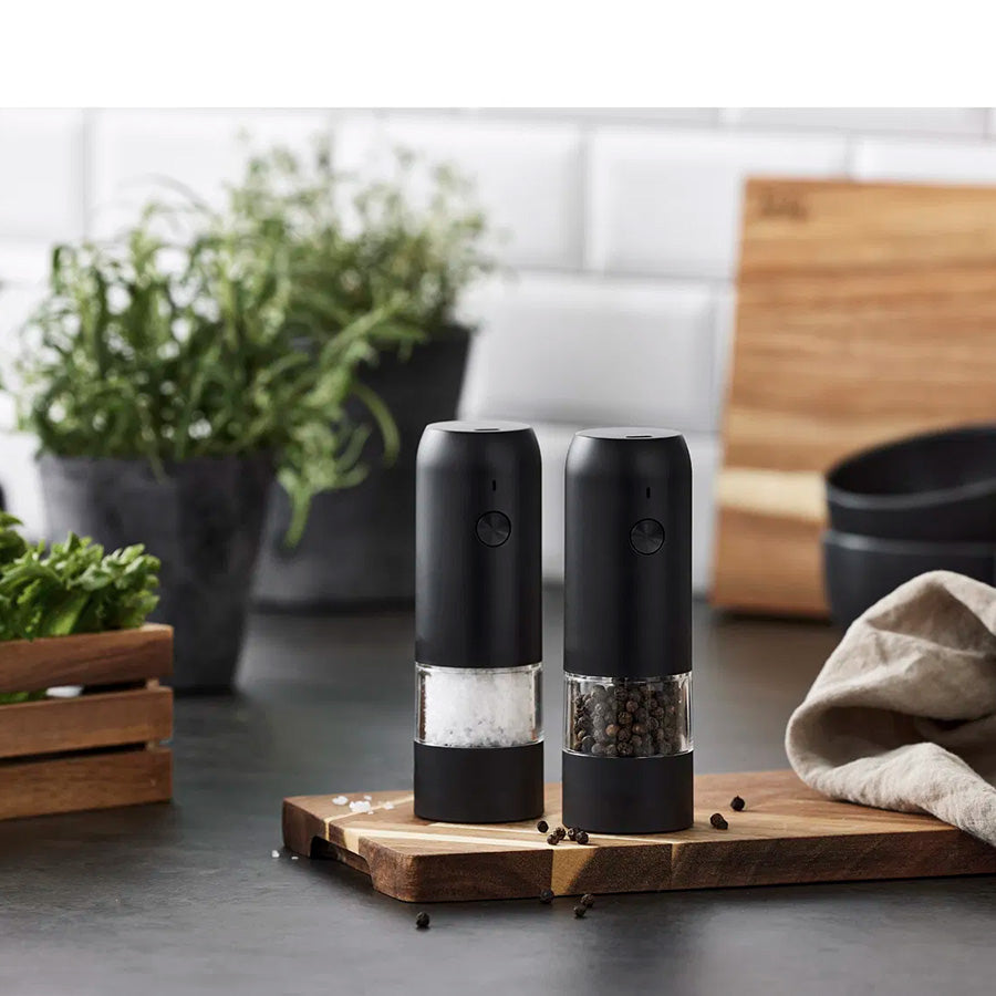 Moderne og funksjonelt elektrisk salt- og pepperkvern sett plassert på en kjøkkenbenk, med klart skille mellom salt og pepper i stilren innredning.
