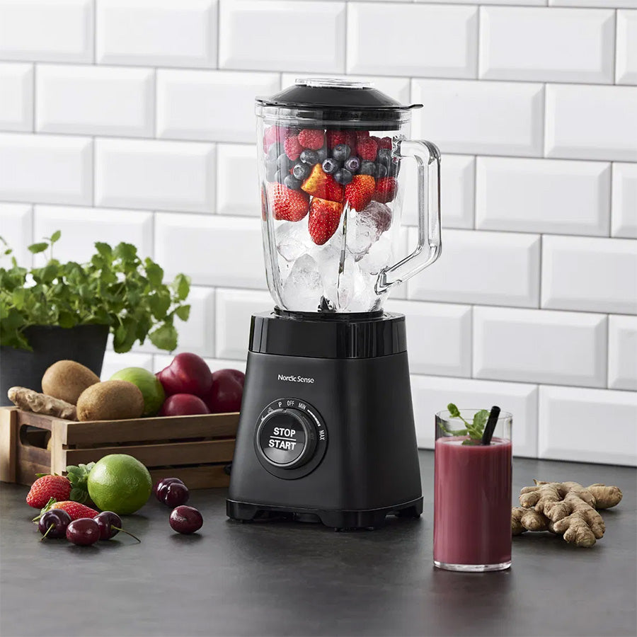 Nordic Sense blender i bruk med ferske bær og isbiter, og en smoothie ferdig på bordet.