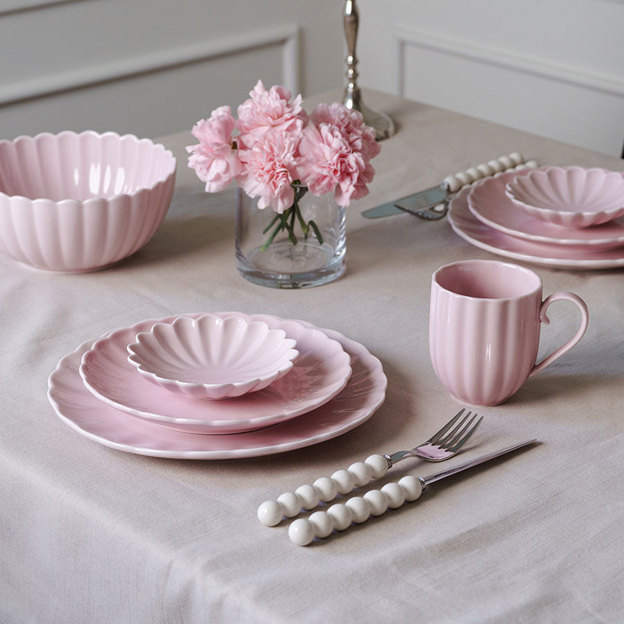 NOVA bestikksett presentert sammen med rosa tallerkener og blomster, fremhever det stilige designet og funksjonaliteten.
