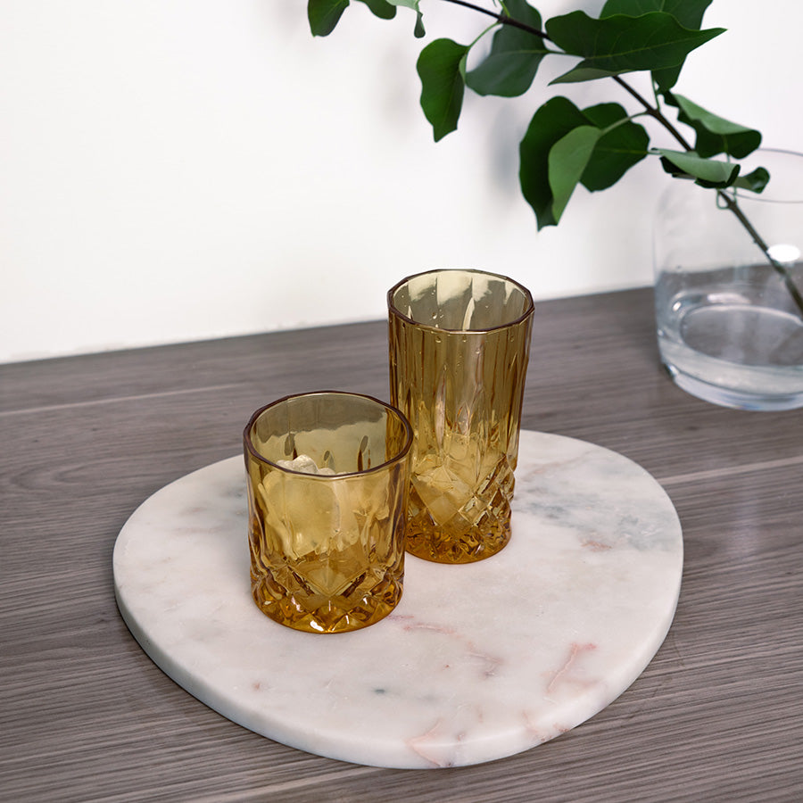 To whiskyglass i amberfarge på en marmorplate, ideelle for whisky eller cocktails, med tidløst design.