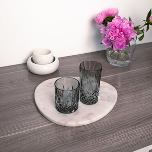 To elegante grå longdrinkglass plassert på en marmorplate, dekorert med blomster, som fremhever deres stil og design.