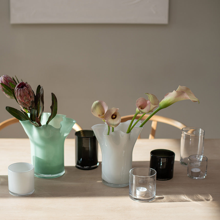 Moderne dekorasjon med svarte lyslykter sammen med blomster i vaser på et bord, som viser hvordan lyslyktene kan brukes i interiørdesign.