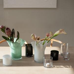 Moderne dekorasjon med svarte lyslykter sammen med blomster i vaser på et bord, som viser hvordan lyslyktene kan brukes i interiørdesign.