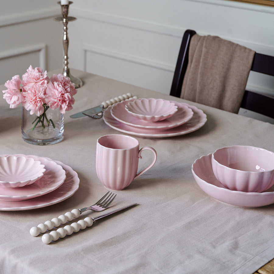 Elegant bordoppsett med dus rosa bolle og matchende tallerkener, kopper og blomsterdekor, ideelt for hyggelige måltider.