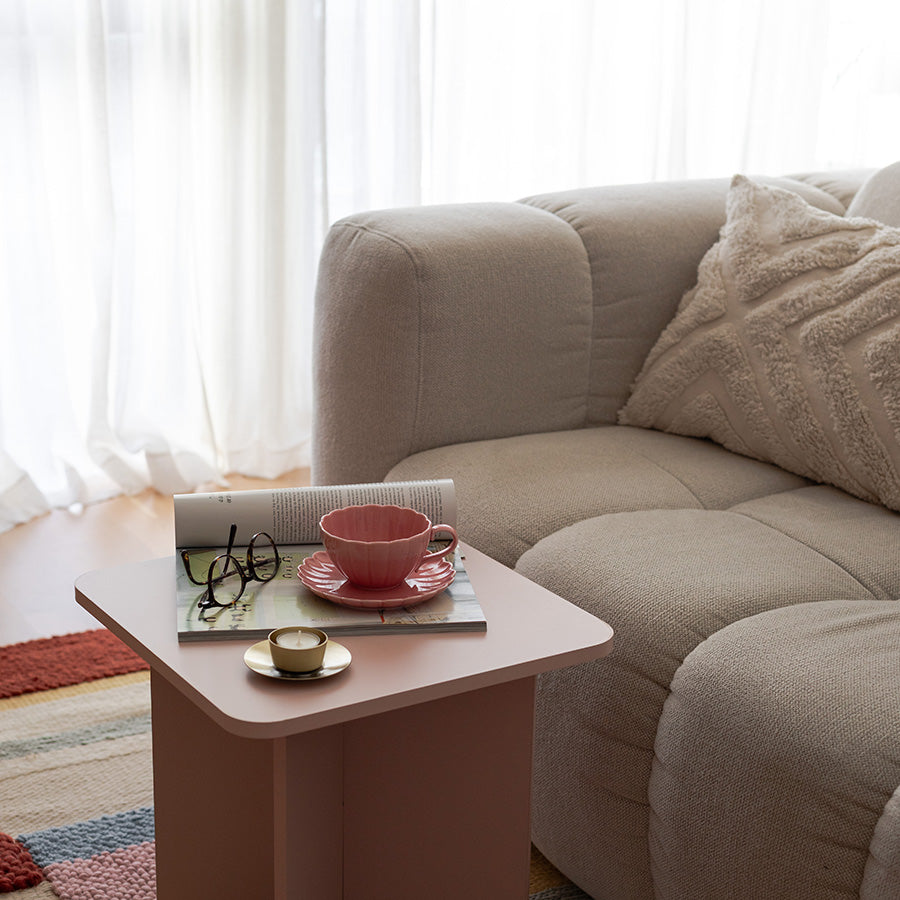Nova Lilly Kopp og Skål 250ml Rosa plassert på et bord ved en sofa, omgivelsene preget av naturlig lys. Perfekt for en koselig kaffepause med Kopp og skål fra NOVA.