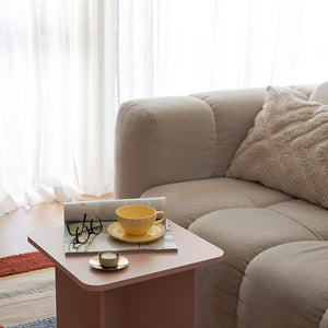Nova Lilly Kopp og Skål 250ml Gul plassert på et rosa bord ved siden av en beige sofa, skapende en innbydende atmosfære for kaffepause med Kopp og skål.