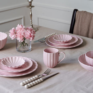 Elegant dekoret borddekorasjon med Lilly krus og matchende tallerkener i dus rosa, perfekt for feminine hjem.