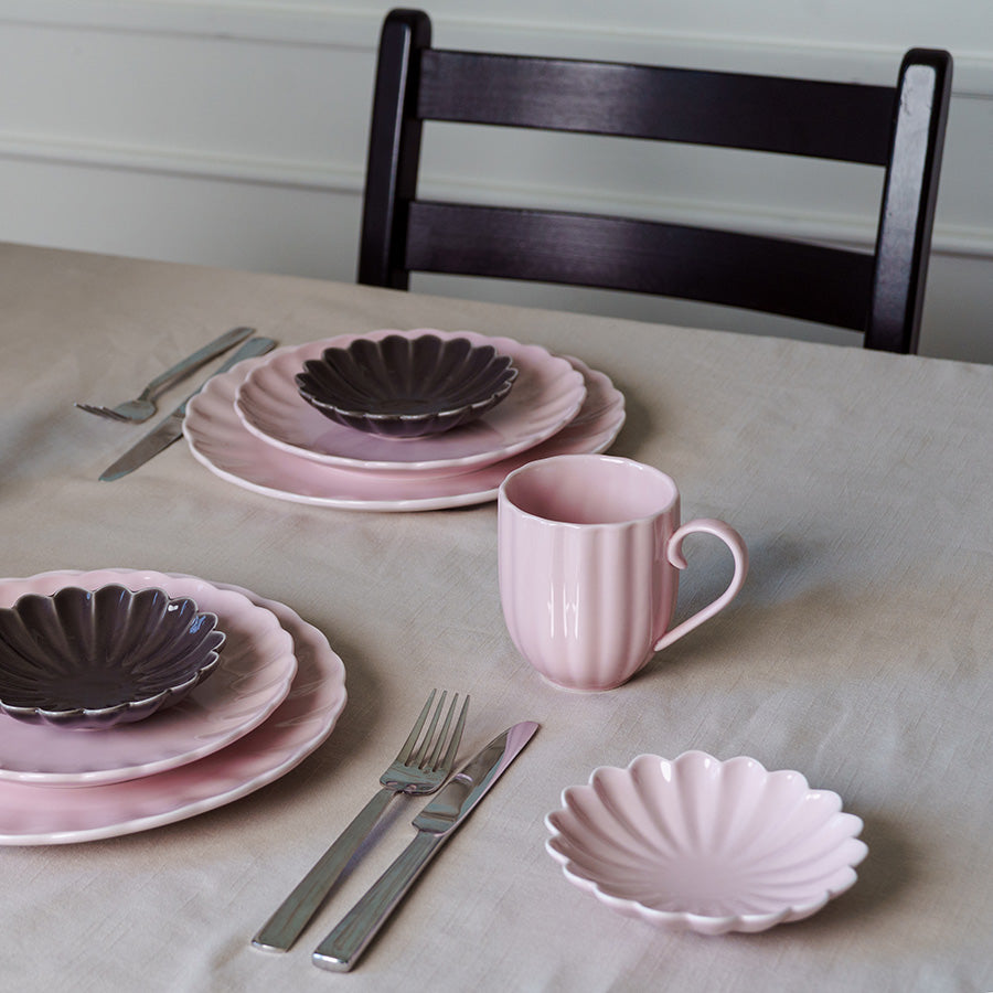 Moderne bordsetting med dus rosa Lilly krus kombinert med en mørk tallerken, ideelt for stilige måltider.