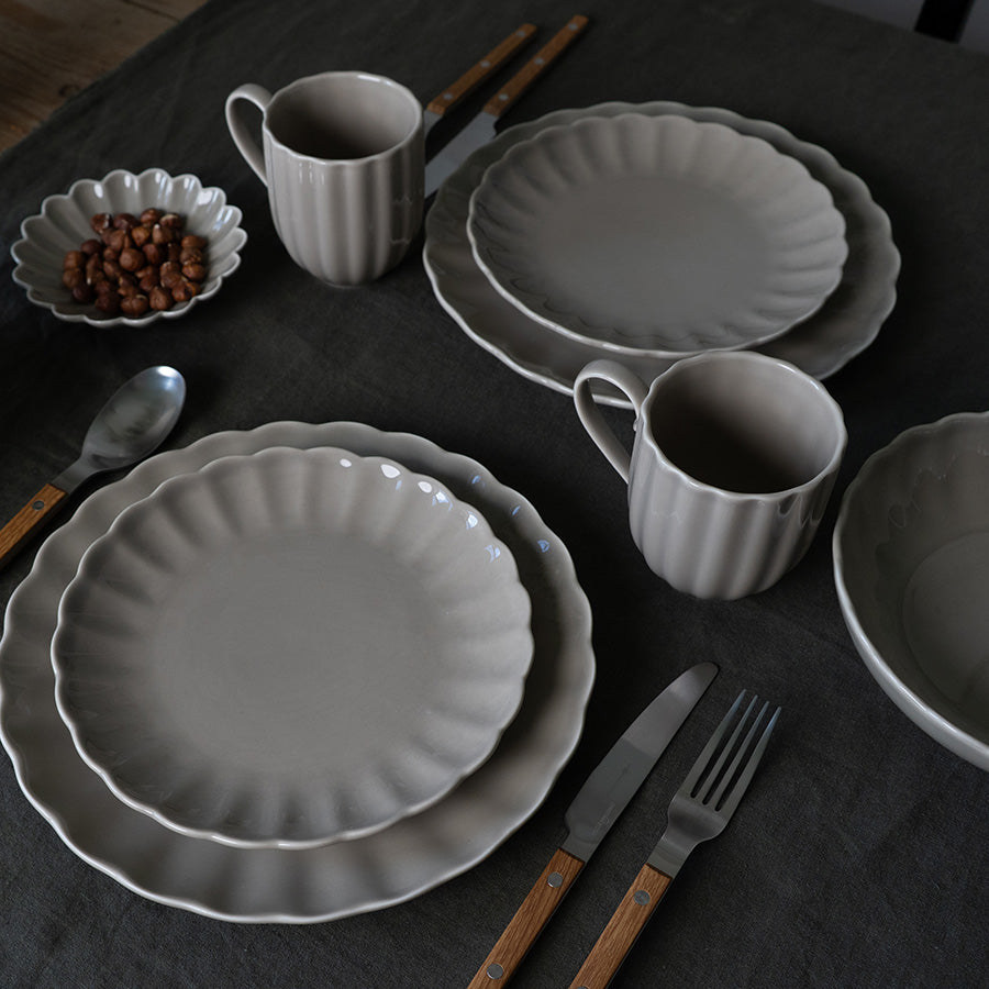 Kaffesett med grått Lilly krus og matchende tallerkener. Elegant borddekking med moderne kjøkkenutstyr.