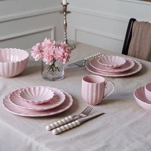 Stilrent dekket bord med Nova Lilly skål i dus rosa, sammen med tallerkener og blomster, perfekt for borddekorasjon.