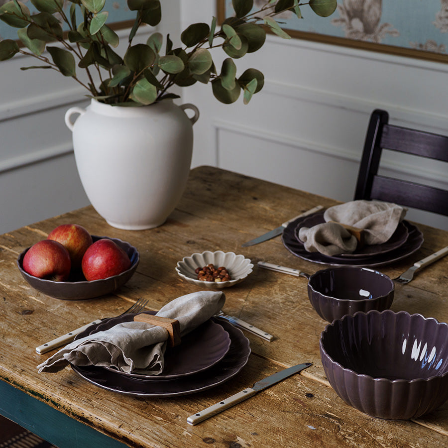 Elegant borddekorasjon med plomme tallerken, skåler og frukt, perfekt for å skape en sofistikert atmosfære.