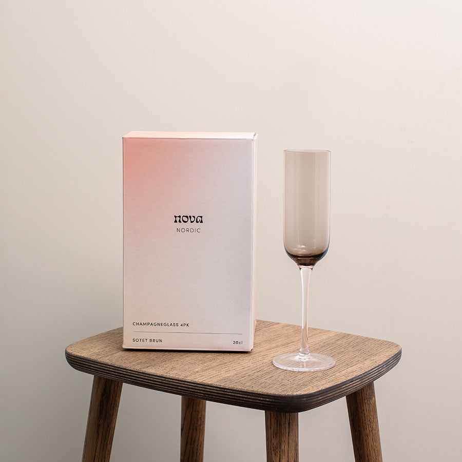 Nordic champagneglass i sotet brunt, presentert i en elegant eske, perfekt for gave eller borddekking, med fokus på nordisk design.