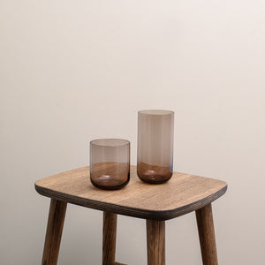 To stilige brune vannglass på et treskjermet bord, perfekte for enhver anledning. Det settet med vannglass fra Nova har en moderne sylinderform og minimalistisk design, og passer til vann, juice eller cocktails.