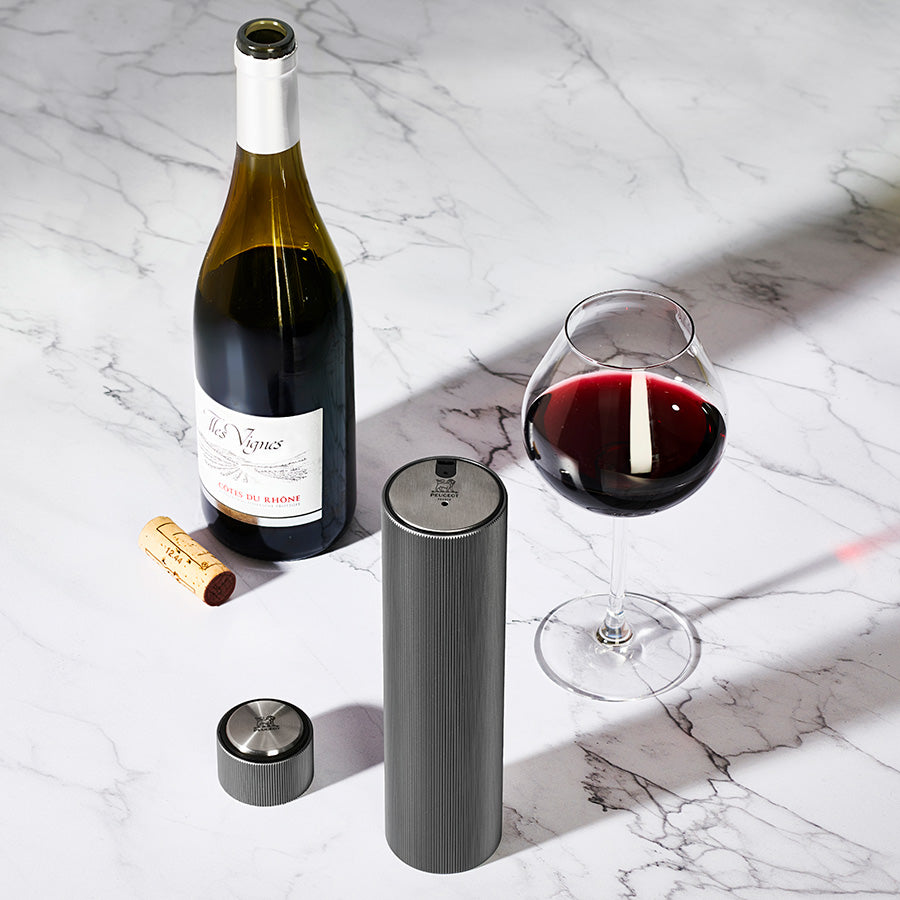 Peugeot Line Reverse Elektrisk Vinopptrekker Carbon med vinflaske og glass med rødvin, ideell som vinopptrekker for elegant servering.