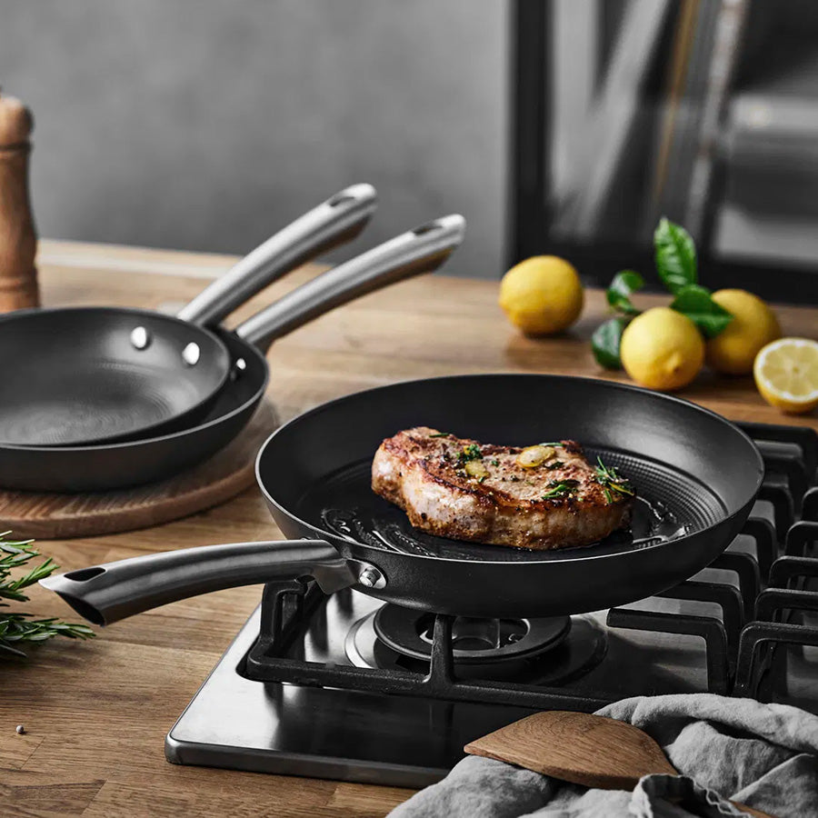 Støpejernspanne i bruk, steker en saftig kjøttbit på komfyren, illustrerer pannen sin høye varmebestandighet.