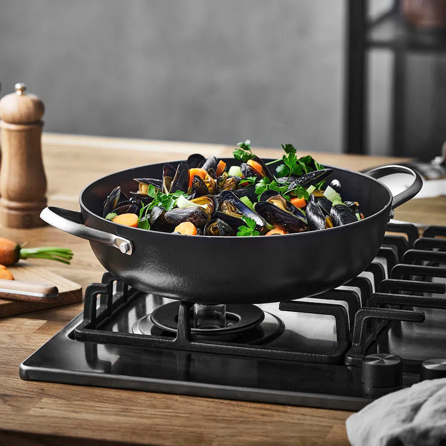 Wokpanne med grønnsaker og muslinger på komfyren, ideell for lynsteking.