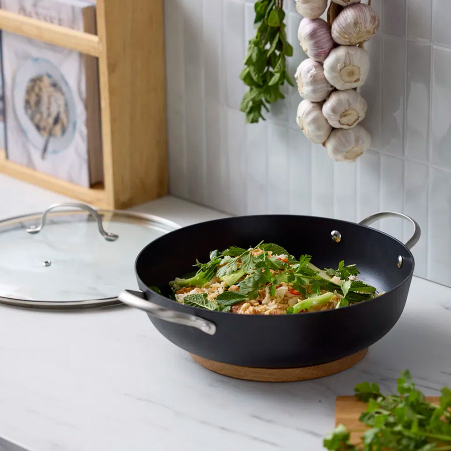 Wokpanne med grønnsaker på et kjøkken, viser hvordan den kan brukes til ulike retter.