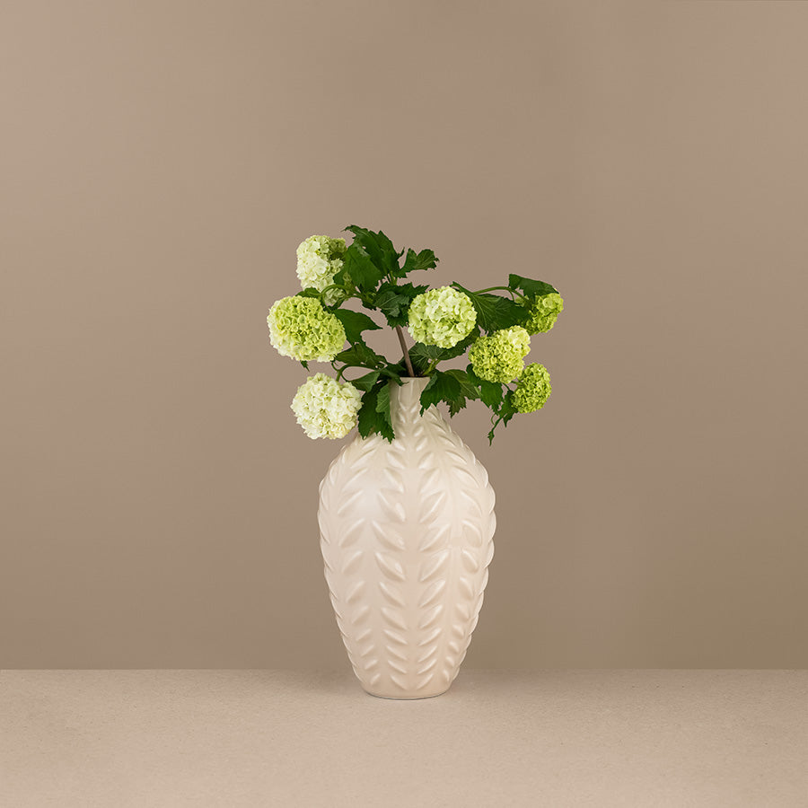 Kremfarget porselensvase dekorert med hvite blomster, perfekt for stilige interiør.