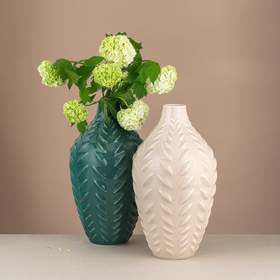To porselensvaser med bladformet design, en kremfarget og en grønn, fylt med grønne blomster for moderne dekor.