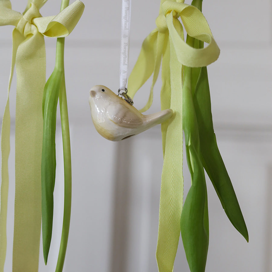 Nærbilde av en lys gul porselensfugl, en av de søte smafugler som gir et bløtt preg til interiøret.