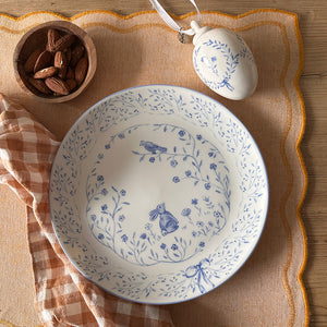 Vår asjett i 20 cm, dekorert med blomster og en blå påskehare, plassert på et bord sammen med nøtter og påskeegg, ideell for vårfrokoster.