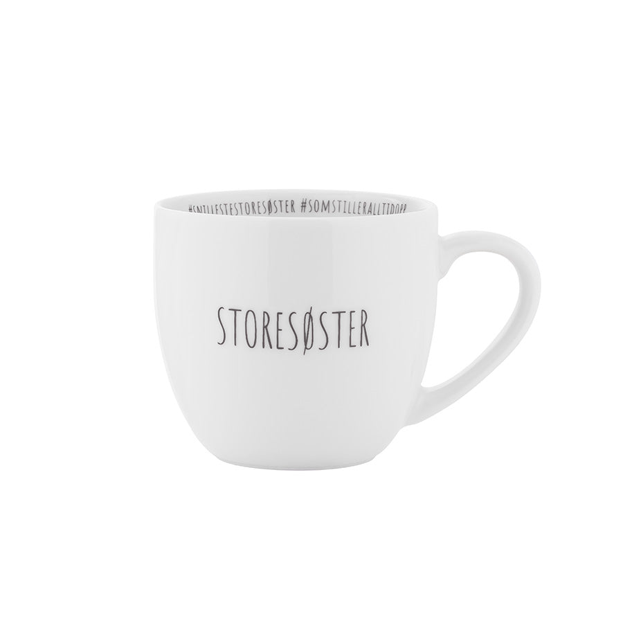 Storesøster krus fra Porsgrunds Porselænsfabrik i hvitt porselen med svart tekst, perfekt for morgenkaffe og te, ideelt som gave til storesøster.