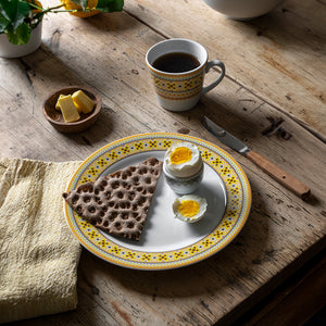 Porsgrunds Porselænsfabrik Ingrid Krus 40cl Gul som serveres med brød og egg, perfekt til en norsk frokosttradisjon.
