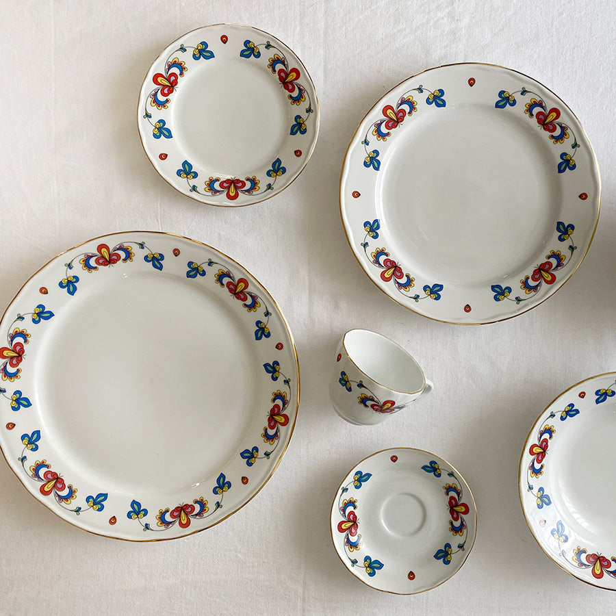 Bondemønster kopp med skål omgitt av matchende tallerkener med norsk blomstermønster
