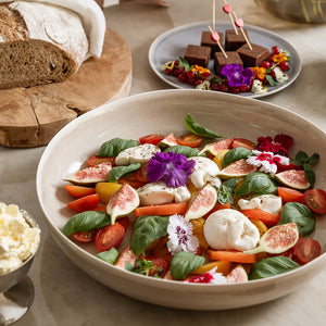 Serveringsbolle med fargerik salat, blomsterdekorasjoner og deilige ingredienser, ideell for festlige anledninger.