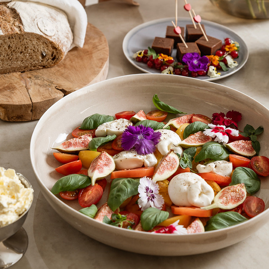 Serveringsbolle med fargerik salat, blomsterdekorasjoner og deilige ingredienser, ideell for festlige anledninger.