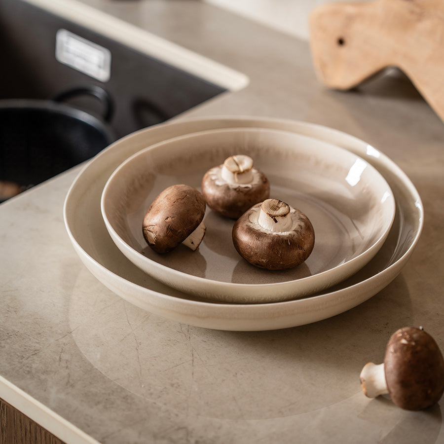 To elegante serveringsboller i lattefarge med sopp, plassert på en kjøkkenbenk, gir en moderne kulinarisk vri.