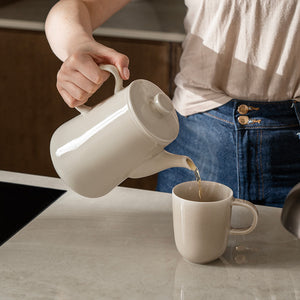 En person heller te fra Ellie tekanne i Latte-farge til en kopp, viser den praktiske og elegante designen, perfekt for te-elskere.