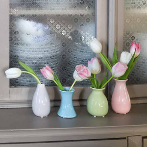 Minivaser med tulipaner ved vinduet, med dekorativt mønster på glasset i bakgrunnen.