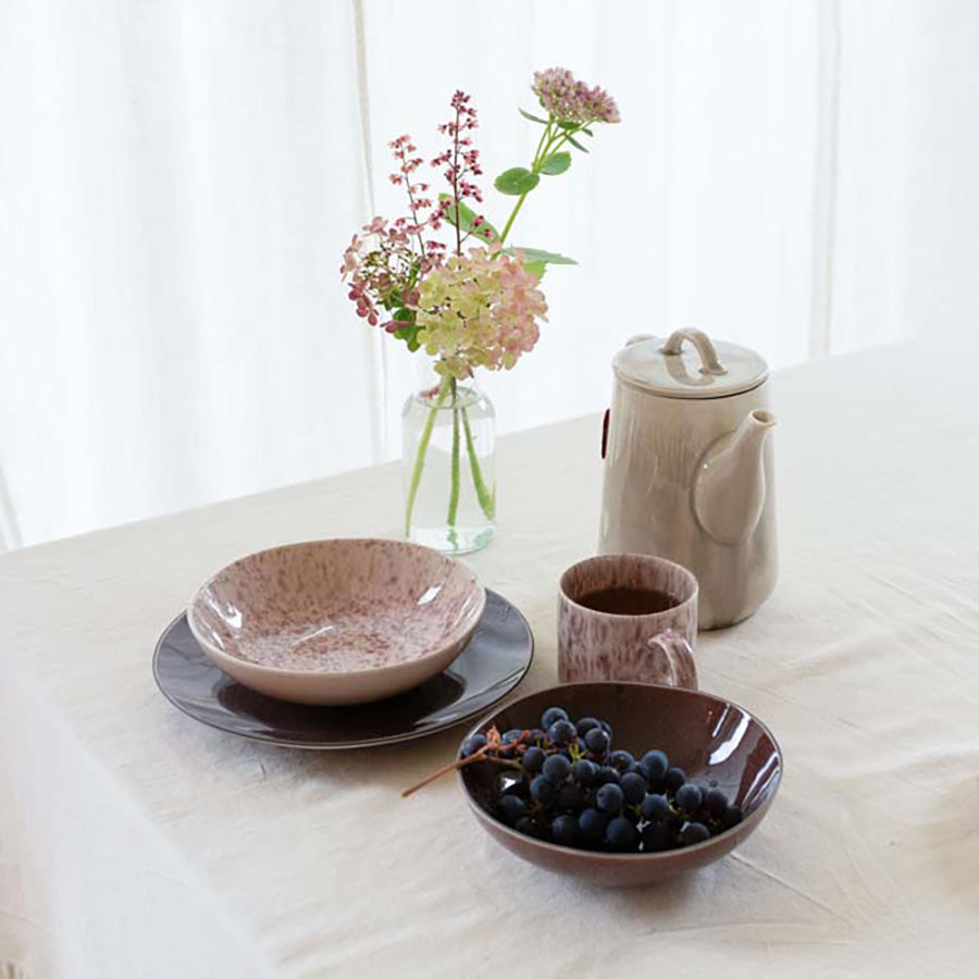 Tallerkener fra Porsgrunds Porselænsfabrik i burgunder og brunt kombinert med en blomsterdekorert vase og serveringsutstyr, for en stilfull borddekking.