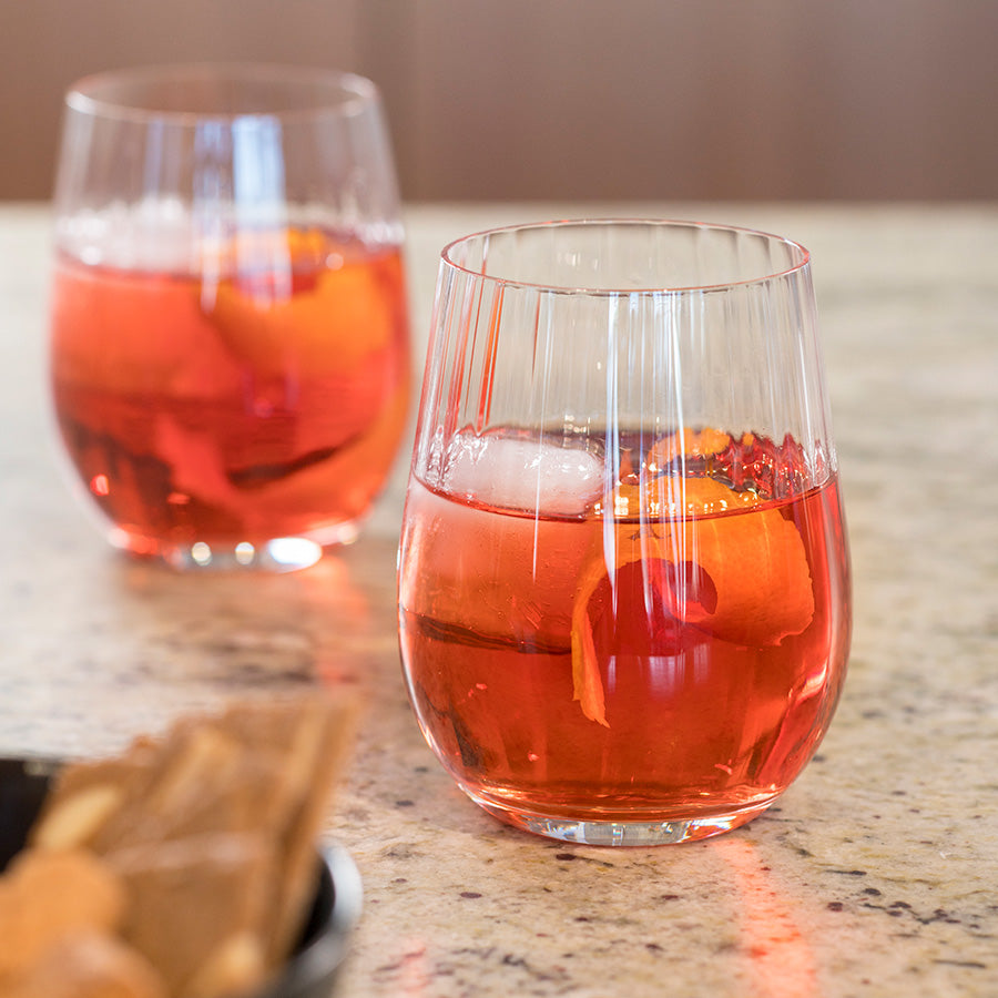 To Riedel whiskyglass fylt med en rød drink, servert på et bord med snacks, ideelt for cocktail- og whiskyopplevelser.