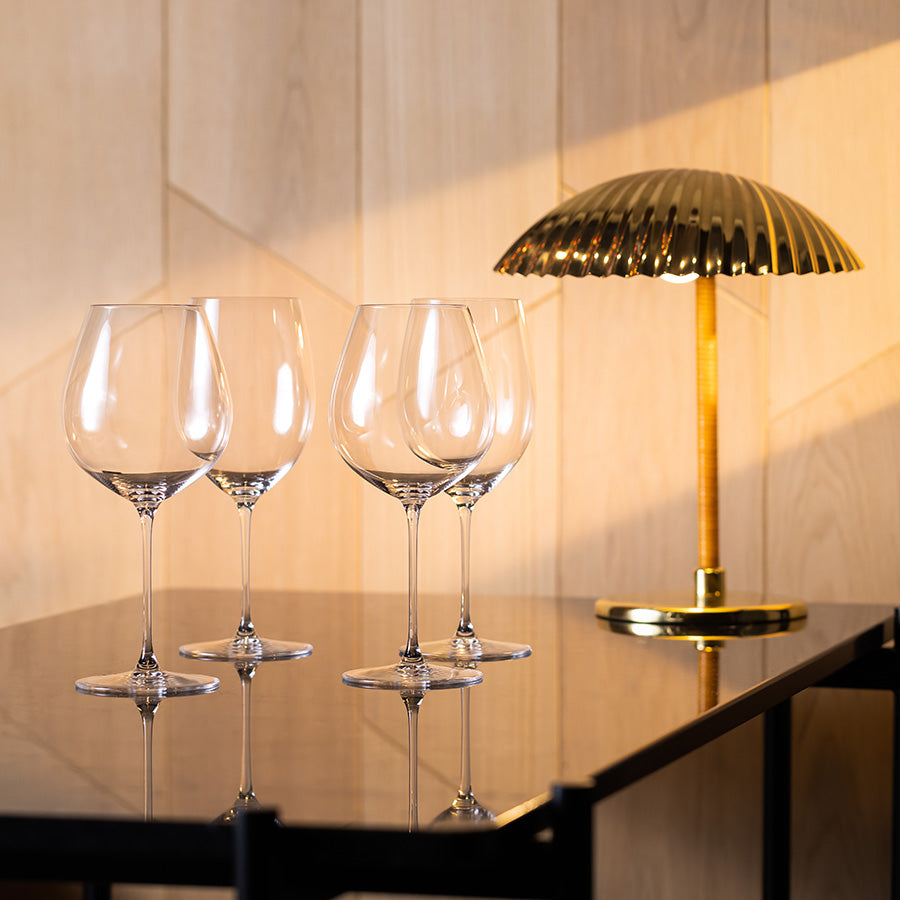 Riedel Vinglass Veritas Pinot Noir 4pk plassert på en moderne bordflate med lys, som fremhever vinglassenes eleganse.