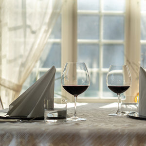 To Riedel rødvinsglass på et lyst bord, perfekt for å nyte Pinot Noir i hyggelige omgivelser.