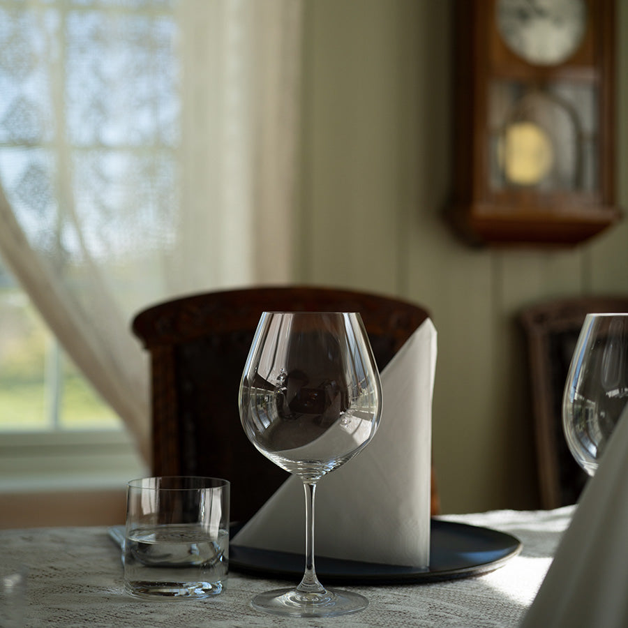 Nært bilde av et Riedel rødvinsglass på et bord, som viser designet og klarheten til glasset.