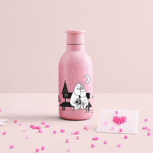 Stelton Drink-IT Mummi termoflaske 0,5L i rosa på et rosa bord, med små perler og en hjerteformet figur ved siden av.