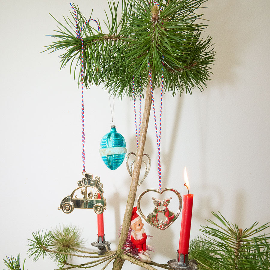 Julestemning med Rosendahl julebil hengende på juletreet, omringet av tradisjonell julepynt, inkludert lys og ornamenter.