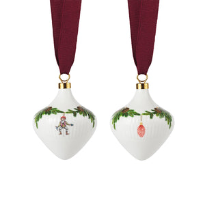 Royal Copenhagen juletrepynt i porselen, sett med to ornamenter med festlig design og rødt silkebånd.
