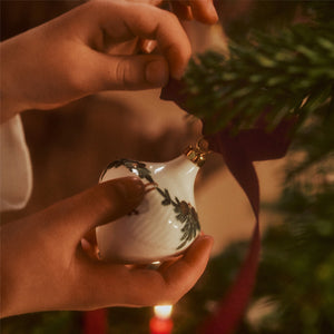 Barn som henger opp Royal Copenhagen juletrepynt på juletreet, med et vakkert ornament fra Stjerneriflet Jul-serien.