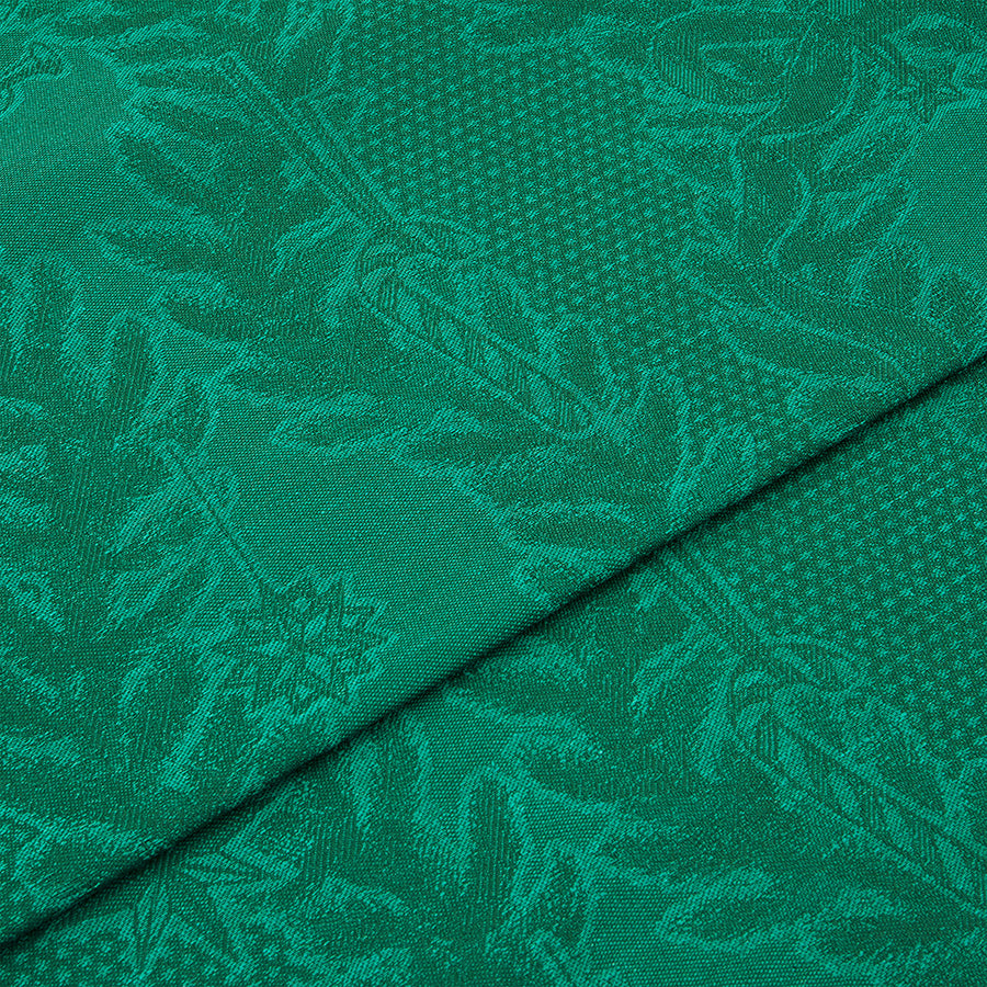 Nærbilde av detaljert grønn juleduk med intrikate mønstre, ideell for julefeiringer. Juleduk med vevde motiver.