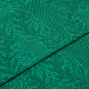 Nærbilde av detaljert grønn juleduk med intrikate mønstre, ideell for julefeiringer. Juleduk med vevde motiver.