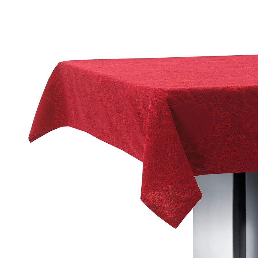 Juleduk i dyp rød farge på et bord, med dekorative detaljer i jacquardvev.